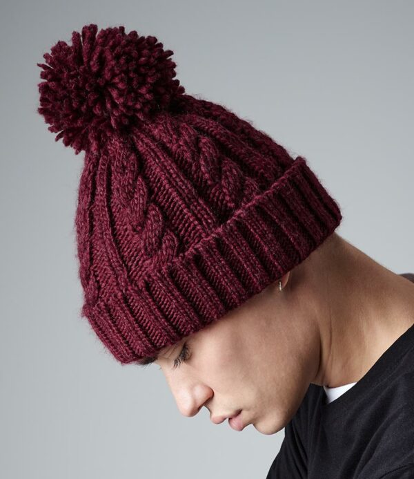Heavy cable knit. Hand knitted feel. Cuffed design. Suprafleece® thermal band. Self colour pom pom. Tear out label.