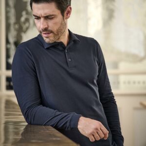 In transition to using OCS certified organic cotton. Fitted style. Flat knit collar with elastane. Taped neck and shoulders. Three button placket with self colour branded buttons. Self fabric cuffs with elastane. Side vents. Twin needle hem.