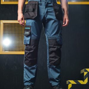 "Slim fit. High shaped back waistband with belt loops and D ring attachments. Inner anti-slip waistband. Zip fly with button and shank button over. Foldaway holster pockets with multiple compartments. Two side pockets. Right hip zip pocket. Reinforced crotch seam. Two multi-function tool and mobile phone pockets on legs with reflective piping. Elasticated panels above knees for ease of movement. Cordura® top loading knee pad pockets. Drawcord hem with reinforced hem overlay. Triple needle stitching. Reflective piping on rear of legs. Branding on left waistband